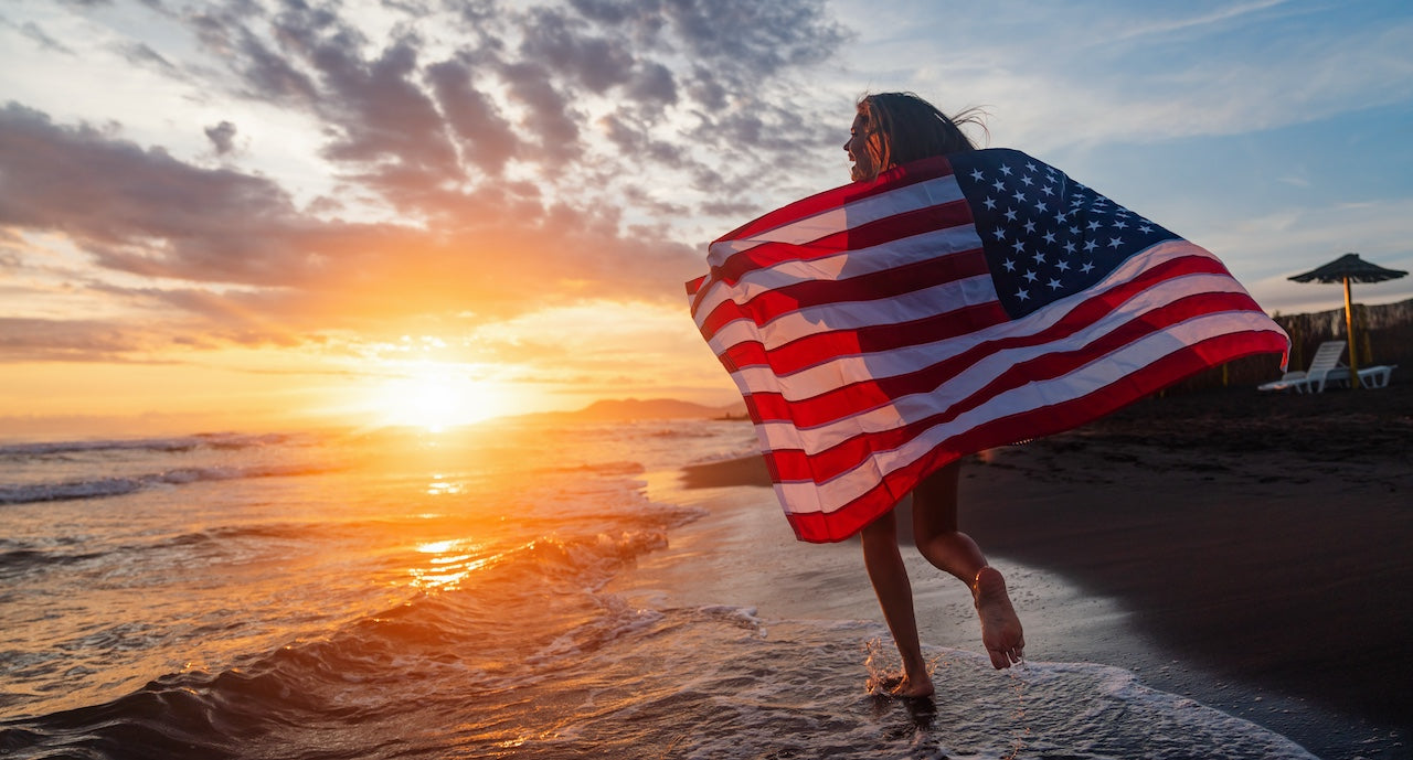 happy-woman-smiling-and-running-on-beach-with-american-flag